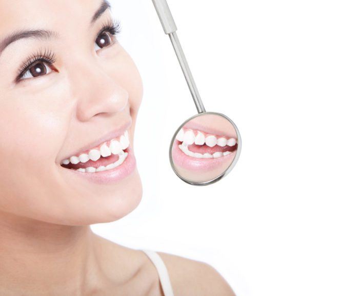 Smiling woman with a dentists mirror dental concerns allentown pa